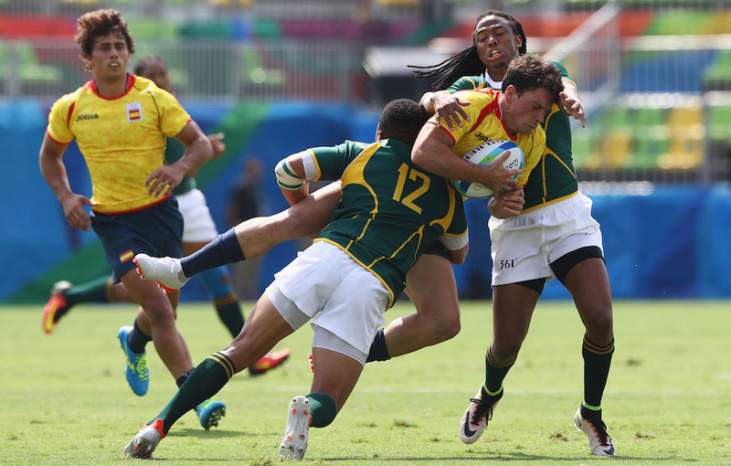 A tender group hug is initiated between Joan Losada of Spain and Juan de Jongh and and Cecil Afrika of South Africa during the Pool B match between Spain and South Africa. Image via Getty.